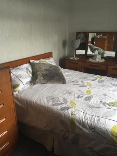 a bed with a pillow and a dresser with a mirror at Farmhouse in Clydebank