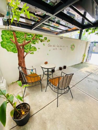 a table and chairs with a tree on a wall at Thong Dong Homestay in Phước Lý