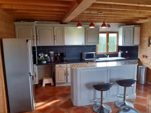 une cuisine avec des armoires blanches et un réfrigérateur blanc dans l'établissement Maison au calme entre Caen et Cabourg, à Bréville-les-Monts