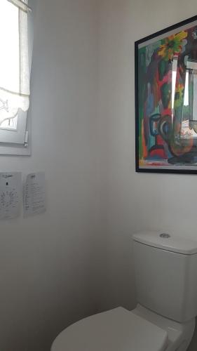 La salle de bains est pourvue de toilettes blanches et d'une peinture murale. dans l'établissement Maison de charme près plage, à La Couarde-sur-Mer