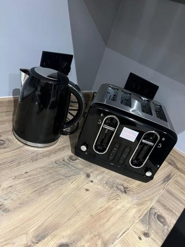 a black tea kettle and a toaster on a wooden table at Galway Glamour in Bircotes
