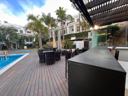 a bar with tables and chairs next to a swimming pool at Doncella Beach , apartamento con vistas al mar in Estepona