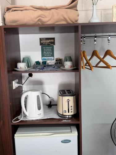 a kitchen shelf with a microwave and a toaster at ALPINE COUNTRY MOTEL plus FREE COFFEE in Cooma