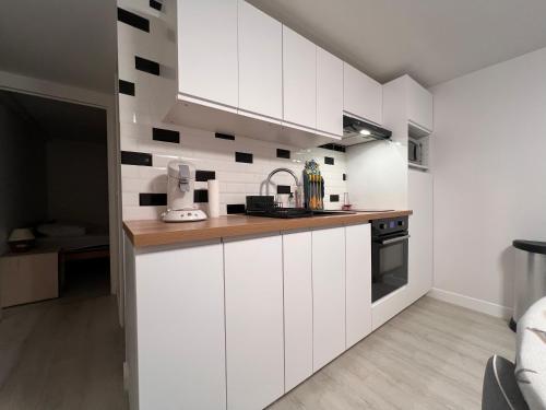 une cuisine avec des armoires blanches et des comptoirs en bois dans l'établissement Appartement T2 cosy proche de Paris, RER à 550m, à Yerres