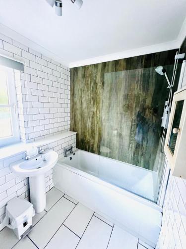 a white bathroom with a sink and a tub and a toilet at 3 Bedroom harbourside apartment, Queensferry, 10 miles from Edinburgh in Queensferry