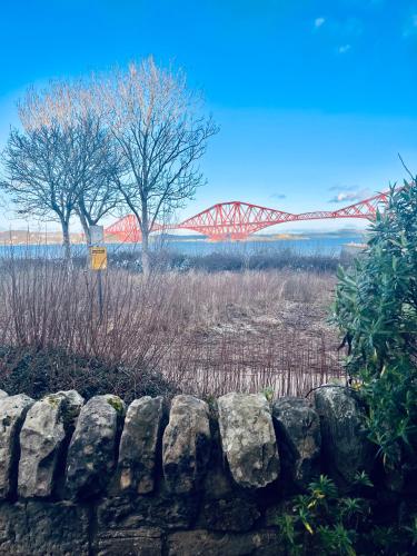 a red bridge in the distance with a stone wall at 3 Bedroom harbourside apartment, Queensferry, 10 miles from Edinburgh in Queensferry