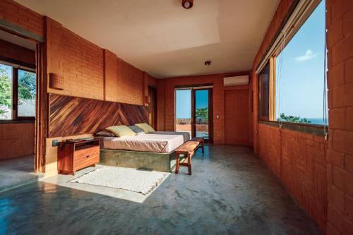 Schlafzimmer mit einem Bett, einer Bank und Fenstern in der Unterkunft Casa Coyote, villa espectacular, 2 albercas in Puerto Ángel