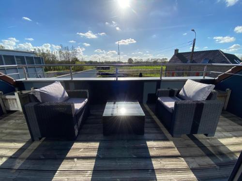 a patio with two chairs and a table on a roof at Escape to Unwind in Putte