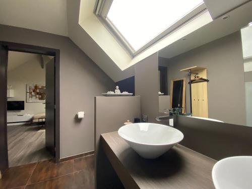 a bathroom with a white sink and a skylight at Escape to Unwind in Putte