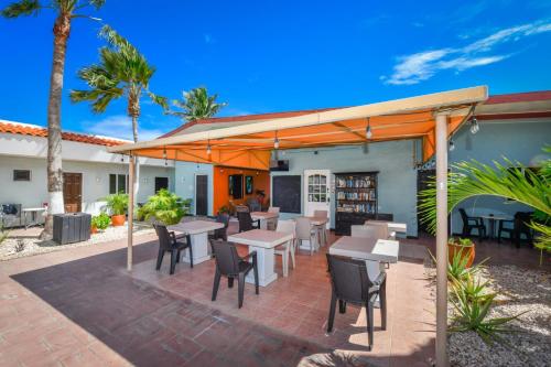 a patio with tables and chairs under an umbrella at Arubiana Inn Hotel in Palm-Eagle Beach