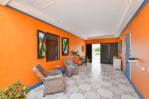 an orange living room with chairs and tables at Arubiana Inn Hotel in Palm-Eagle Beach