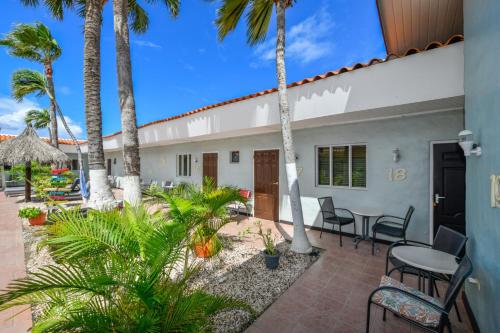 a patio with palm trees and tables and chairs at Arubiana Inn Hotel in Palm-Eagle Beach