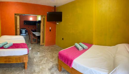 two beds in a room with orange and yellow walls at CASA RAQUEL in Rincon de Guayabitos