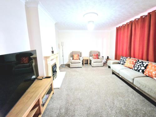 a living room with a couch and a tv at Cosy Luxurious Large 3 bedroom house, free parking, free WiFi in Havering atte Bower