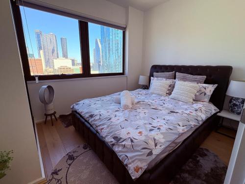 a bedroom with a large bed with a large window at “Urban Oasis ” Central emporium apt ,Free Parking in Melbourne