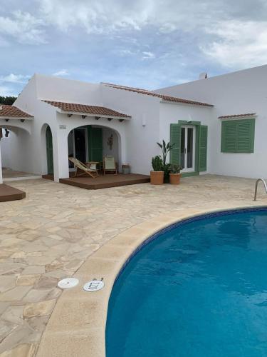 une villa avec piscine devant une maison dans l'établissement Cales de Menorca 6, à Cala Blanca