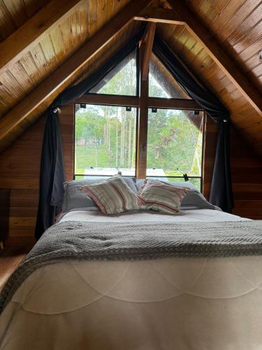 a bed in a room with a large window at Chalé Brisa Verde in Rio dos Cedros