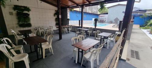 a restaurant with tables and chairs and a swimming pool at Pousada Boramar in Boracéia