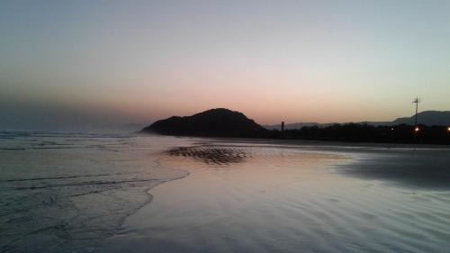 a beach at sunset with a mountain in the background at Pousada Boramar in Boracéia