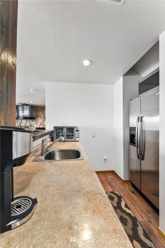 a kitchen with a sink and a stainless steel refrigerator at Beautiful Private Lake Lodge with Private Dock and Mountain Views in Spanaway