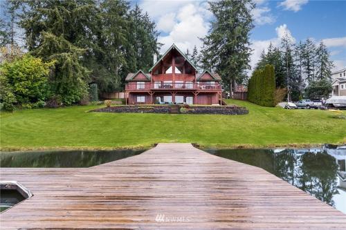 a wooden walkway leading to a house on a lake at Beautiful Private Lake Lodge with Private Dock and Mountain Views in Spanaway