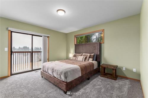 a bedroom with a large bed and a large window at Beautiful Private Lake Lodge with Private Dock and Mountain Views in Spanaway