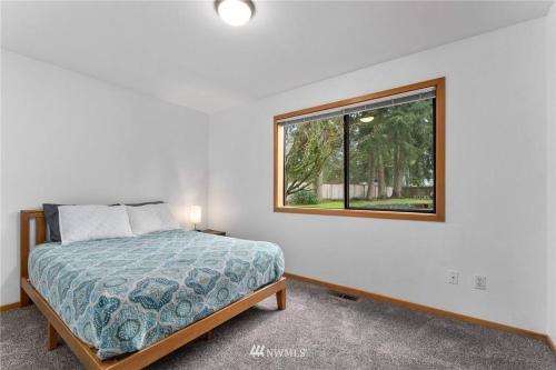 a bedroom with a bed and a window at Beautiful Private Lake Lodge with Private Dock and Mountain Views in Spanaway