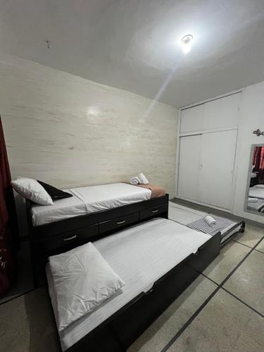 two beds are in a room with a wall at Apartaestudio Amoblado Estadio in Medellín