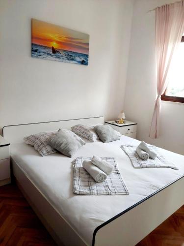 a white bed with towels on it in a bedroom at Apartments with parking space Postira, Brac - 700 in Postira