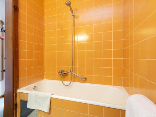 an orange tiled bathroom with a tub and a shower at Brixen Alpin Living Top 3 in Brixen im Thale