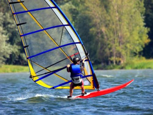 a man riding a wind sail on the water at Serene Luxe Lakeside Stay in Boussu-lez-Walcourt