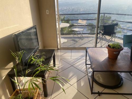 a room with plants and a table and a balcony at Habitación en departamento con vista a la ciudad in Tijuana