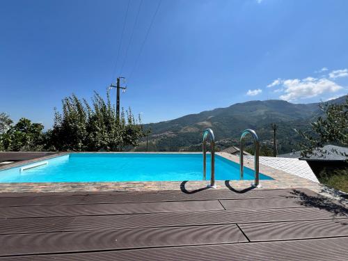 a blue swimming pool with mountains in the background at Casa do Julien Mountain Experience in Vila Real