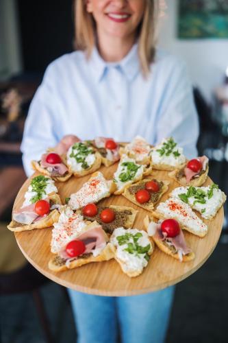 a woman holding a platter of food on a plate at Casablanca Boutique Bed&Breakfast in Zagreb