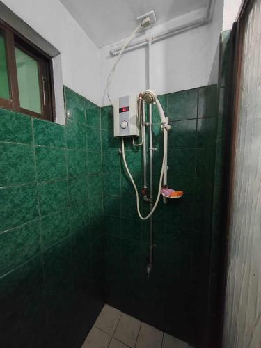 a shower in a bathroom with green tiles at SOLO ROOM near burnham park in Baguio