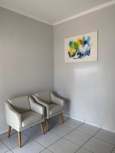 a room with two chairs and a painting on the wall at Casa jardim ao lado da BR-242 in Barreiras