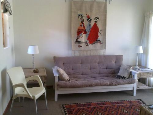 a living room with a couch and a painting on the wall at Sandstone Chameleon Guest House in Fouriesburg