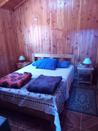 a bedroom with a bed with blue pillows on it at Lican Ray Cabañas Los Primos in Licán Ray