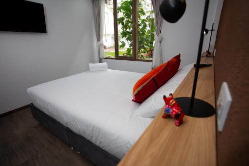 a bedroom with a white bed with red pillows and a window at MUJU hotel by Ämak in Urubamba
