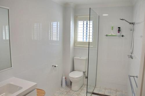 a white bathroom with a toilet and a shower at Jaspa - River Views - Bring your own linen in South West Rocks