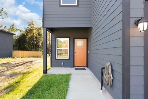 an orange door on the side of a house at 3BR 2 & half Bath Townhouse Modern Spacious Retreat Near Lake Conroe! in Conroe