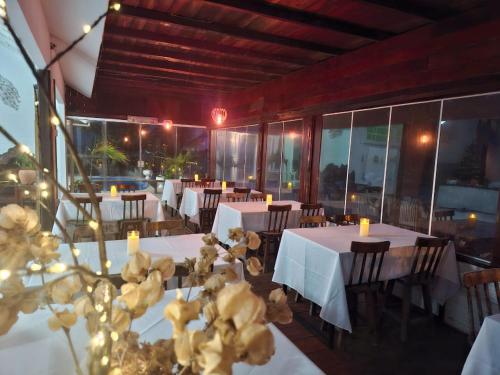a restaurant with tables and chairs with white tables and flowers at Aquavit pousada e comedoria in Jacumã