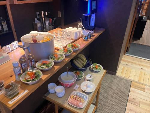 a buffet with bowls of food on a table at Restmance Pension Woody Hill in Iiyama