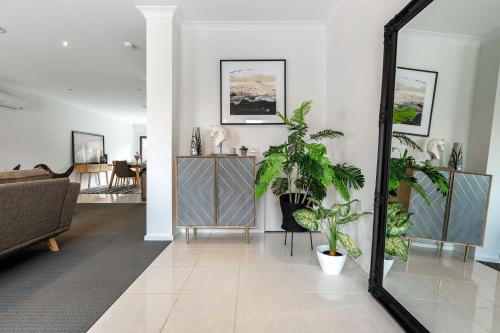 a living room with potted plants and a mirror at VAQUAY Contempo In Flemington in Melbourne