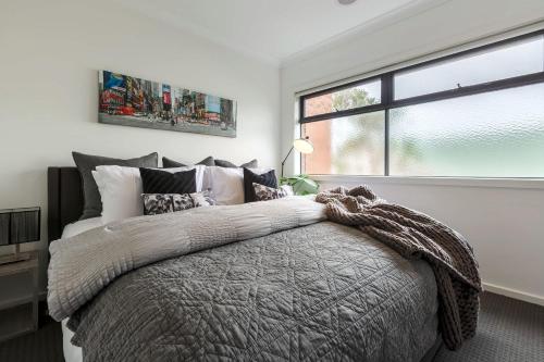 a bedroom with a large bed and a window at VAQUAY Contempo In Flemington in Melbourne