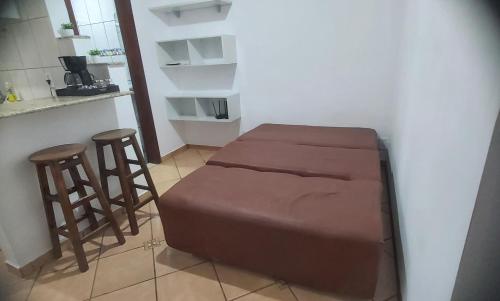 a room with a bed and two bar stools at Brisa do Mar in Caraguatatuba