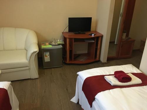 a hotel room with a bed and a chair and a television at Abszolút Hotel és Panzió in Nyírbátor