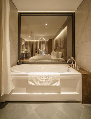 a bath tub in a bathroom with a large mirror at Nhat Ha Lavish Hotel in Ho Chi Minh City