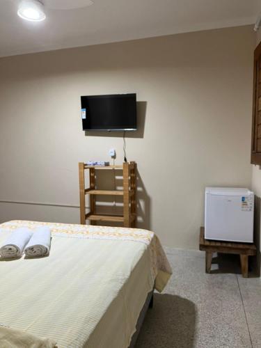 a bedroom with a bed and a flat screen tv at Pousada Maria Moura in Camacari