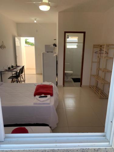 a bedroom with a white bed and a kitchen and a table at Loft ROMA para Casais, em Iguaba Grande, 3 Pessoas, 150 metros da praia in Iguaba Grande
